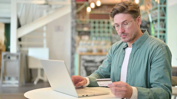 Erfolg beim Online-Bezahlen am Laptop von Mann mittleren Alters im Café — Stockfoto