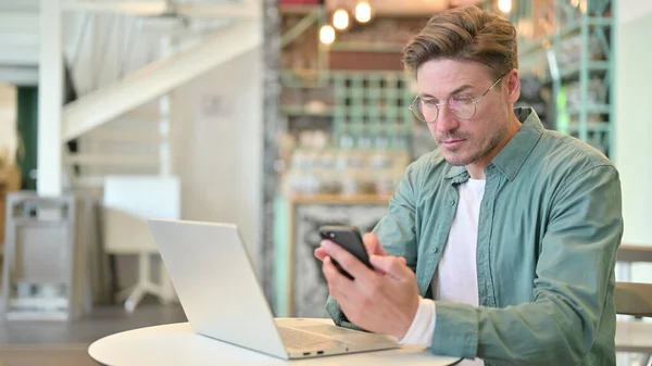 Utilisation du smartphone par l'homme du Moyen Âge avec ordinateur portable dans Cafe — Photo