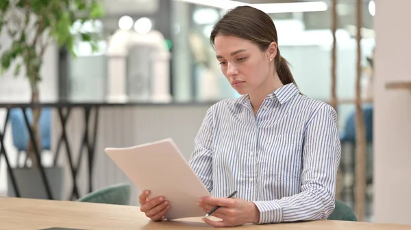 オフィスで文書を読む若い女性に焦点を当て — ストック写真