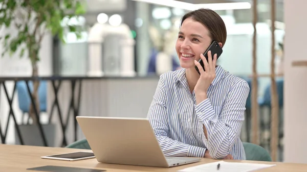 オフィスで電話で話すノートパソコンを持つ若い女性 — ストック写真