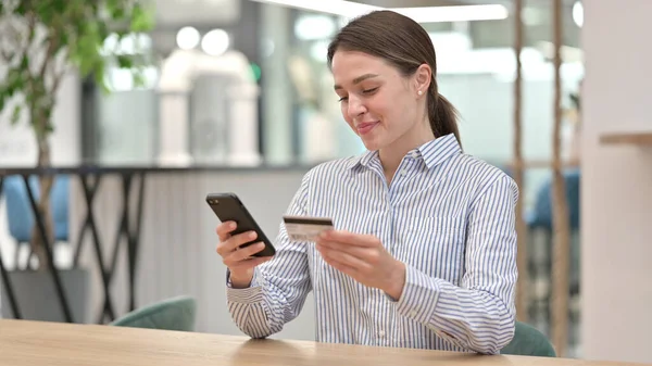 オンライン決済に成功した若い女性がオフィスでスマートフォンで — ストック写真