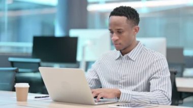 Ofiste dizüstü bilgisayar kullanırken kameraya bakan Afrikalı Çekici İşadamı