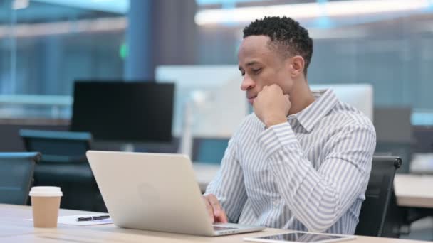 Jonge Afrikaanse zakenman met laptop denken op het werk — Stockvideo