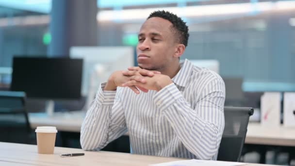若いアフリカのビジネスマンがオフィスで考えて座っている — ストック動画