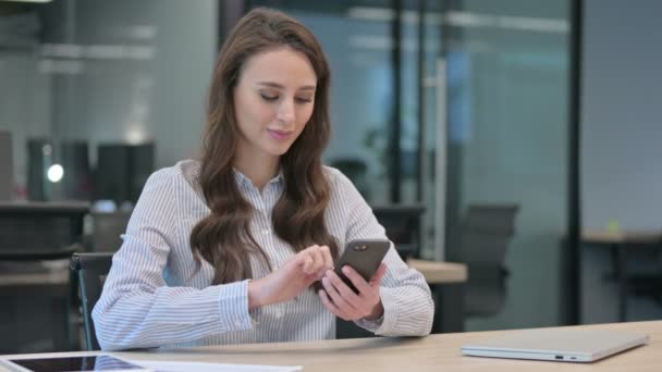 Atrakcyjny młody bizneswoman za pomocą smartfona w pracy — Wideo stockowe
