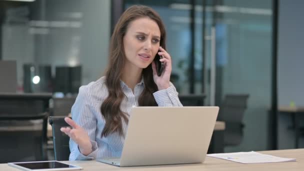 Angry Businesswoman Falando em Smartphone enquanto estiver usando Laptop — Vídeo de Stock