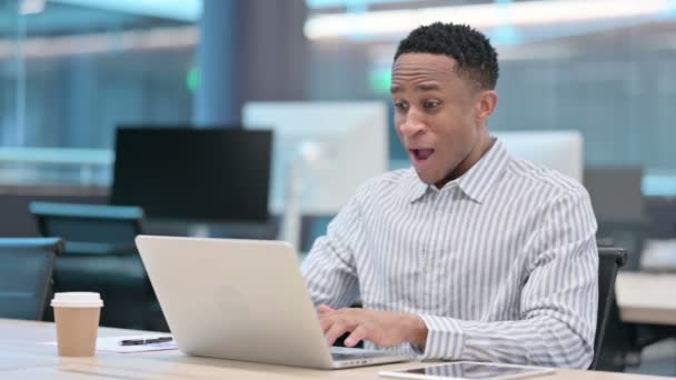 Sikeres afrikai üzletember ünnepli a laptopon a munkahelyen — Stock videók
