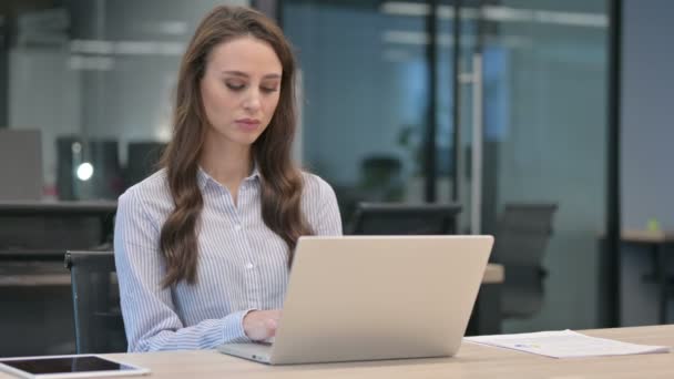 Joven empresaria que piensa mientras usa el ordenador portátil en el trabajo — Vídeo de stock