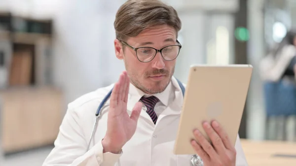 Mężczyzna lekarz machanie na wideo czat na tablecie — Zdjęcie stockowe