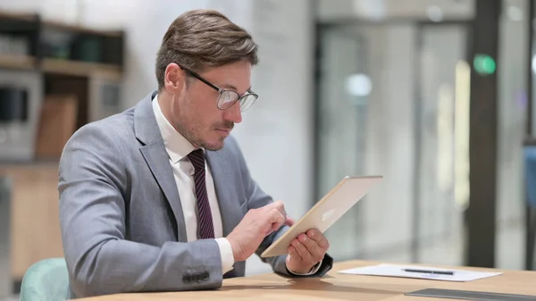 Σοβαρός επαγγελματίας επιχειρηματίας που χρησιμοποιεί tablet στο γραφείο — Φωτογραφία Αρχείου