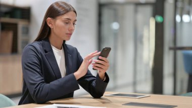 Ofiste akıllı telefon kullanan ciddi bir iş kadını. 