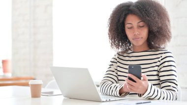 Akıllı telefon kullanan dizüstü bilgisayarı olan kadın