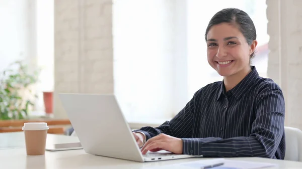 Dizüstü bilgisayarlı neşeli Hintli kadın Kameraya gülümsüyor 