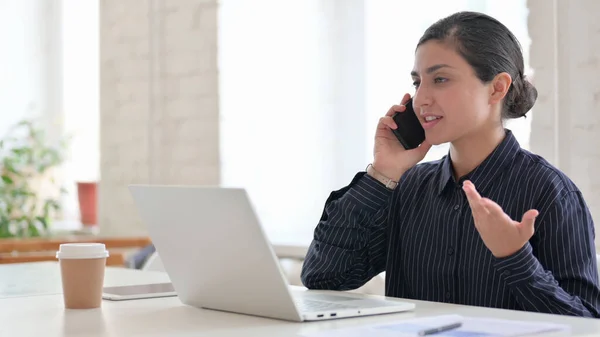 Mulher indiana jovem com laptop conversando no telefone — Fotografia de Stock