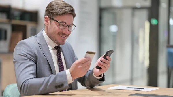 Affärsman med framgångsrik online-betalning på smartphone i Office — Stockfoto