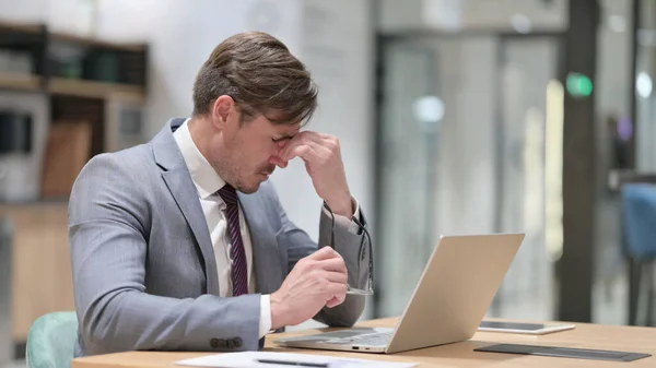 Αγχωμένος επιχειρηματίας με φορητό υπολογιστή που έχει πονοκέφαλο στο γραφείο — Φωτογραφία Αρχείου