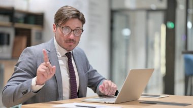 Dizüstü bilgisayarlı ciddi bir iş adamı Parmak İşaretine Hayır diyor