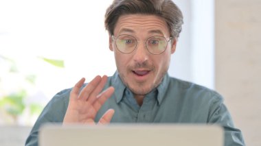 Bilgisayarda konuşan orta yaşlı adamın portresi.