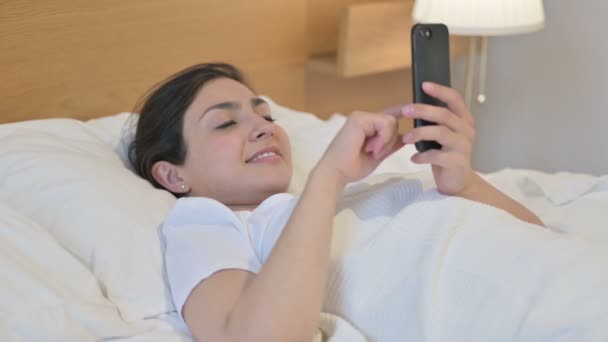 Νεαρή Ινδή γυναίκα χρησιμοποιώντας Smartphone ενώ κοιμάται στο κρεβάτι — Αρχείο Βίντεο