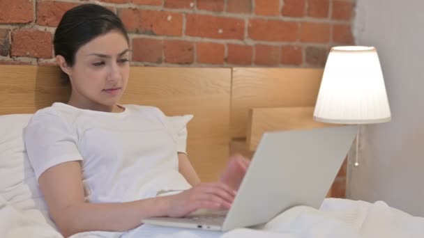 Junge Inderin mit Nackenschmerzen arbeitet im Bett am Laptop — Stockvideo
