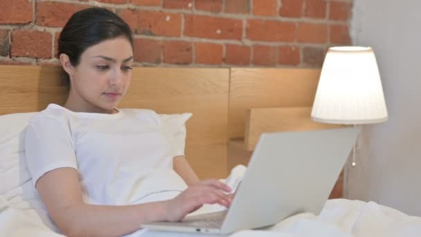 Mujer india joven con el ordenador portátil diciendo no por el movimiento de cabeza en la cama — Vídeos de Stock