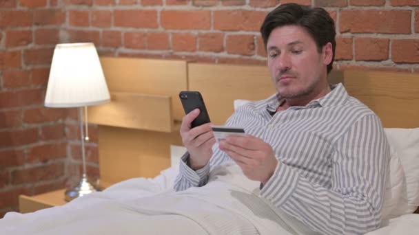 Uomo di mezza età che effettua il pagamento online su smartphone a letto — Video Stock