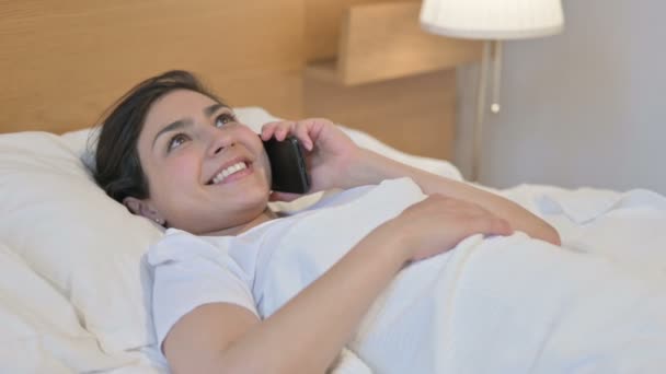 Νεαρή Ινδή γυναίκα μιλάει στο τηλέφωνο ενώ κοιμάται στο κρεβάτι — Αρχείο Βίντεο
