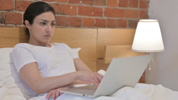 Mujer india joven pensando y trabajando en el ordenador portátil en la cama — Vídeos de Stock