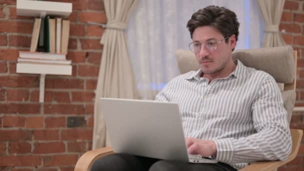 Мужчина средних лет с ноутбуком празднует успех на диване — стоковое видео