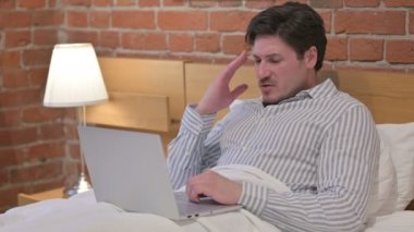 Laptop 'u olan orta yaşlı adamın yatağında başı ağrıyor.