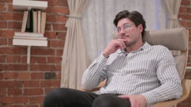 Orta yaşlı adam koltukta oturup düşünüyor.