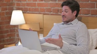 Orta yaşlı adam laptopta video görüşmesi yapıyor.