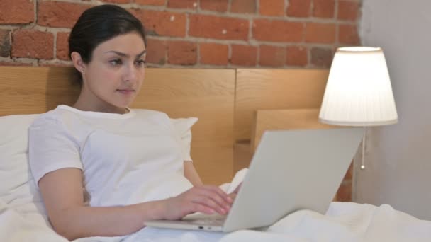 Jovem mulher indiana reagindo a perda no laptop na cama — Vídeo de Stock