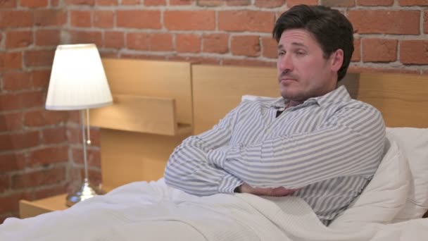 Hombre de mediana edad pensando mientras está sentado en la cama — Vídeo de stock