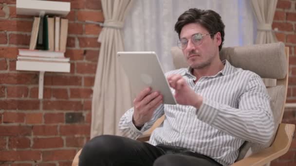 Hombre de mediana edad usando Tablet en el sofá — Vídeo de stock