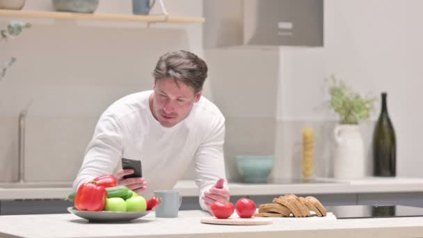 Mężczyzna robi zdjęcie owoców na smartfonie w kuchni — Wideo stockowe
