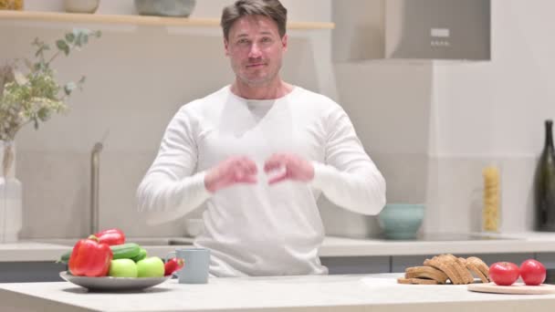 Uomo che fa forma di cuore da mani mentre in cucina — Video Stock
