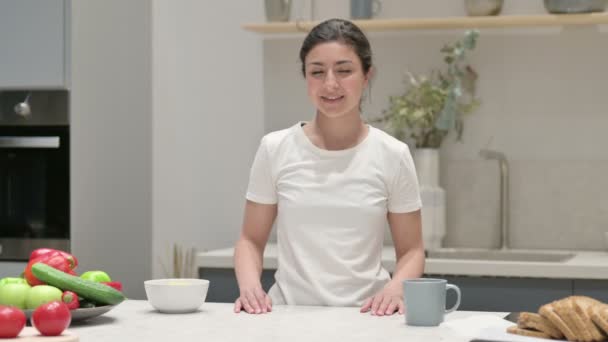 Mujer india sonriendo a la cámara mientras está de pie en la cocina — Vídeos de Stock