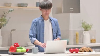 Asyalı Adam Mutfakta Dizüstü bilgisayar kullanırken Başarı Kutlaması