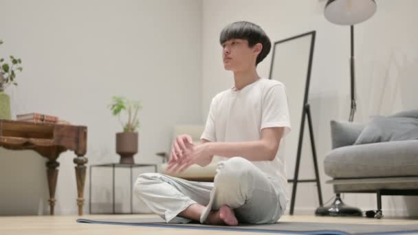 Fredlig asiatisk man mediterar på yogamattan hemma — Stockvideo