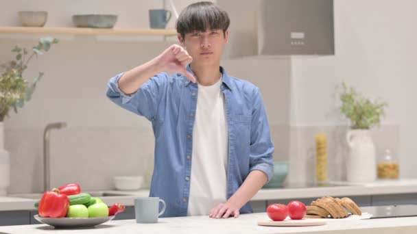 Asiático hombre mostrando pulgares abajo mientras de pie en cocina — Vídeos de Stock