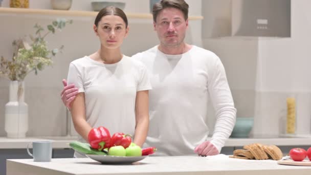 Gemischtes Paar blickt in Küche auf Kamera — Stockvideo