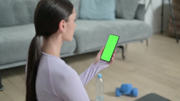 Lateinamerikanerin nutzt Smartphone mit Chroma-Bildschirm auf Yoga-Matte — Stockvideo