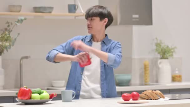 Asiatisk man leker med grönsaker och dansar i köket — Stockvideo