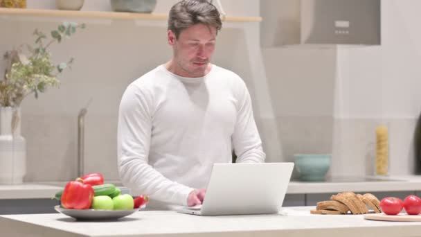 Uomo che lavora sul computer portatile in cucina — Video Stock