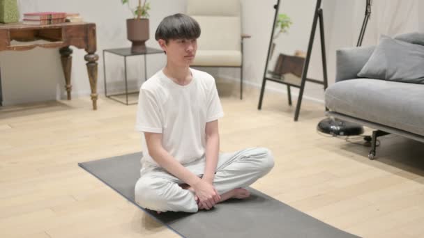 Азиатский мужчина медитирует на коврике для йоги дома — стоковое видео