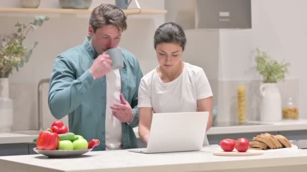 Coppia mista di razza che lavora sul computer portatile in cucina — Video Stock