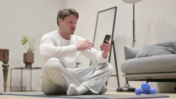 Homme parlant sur appel vidéo sur Smartphone sur tapis de yoga — Video