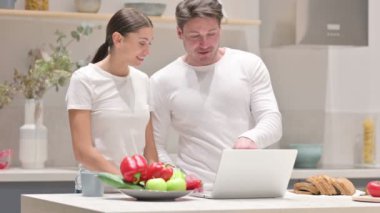 Karışık Yarış Çifti Mutfakta Dizüstü bilgisayarda çalışıyor