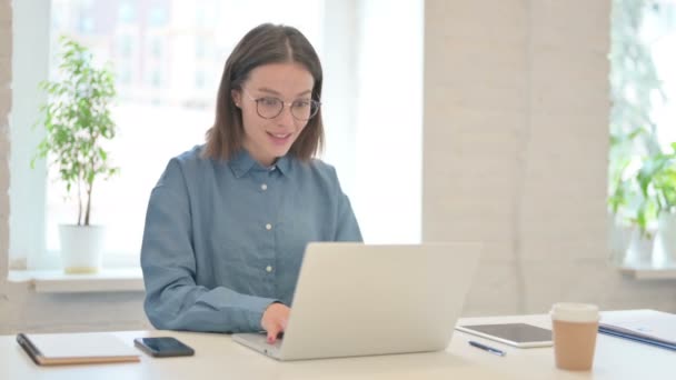 Succesvolle jonge vrouw viert feest op laptop op het werk — Stockvideo